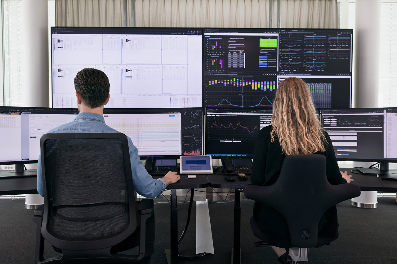 To ansatte jobber foran mange skjermer